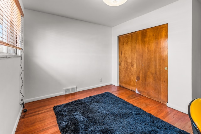 unfurnished bedroom with baseboards, visible vents, and wood-type flooring