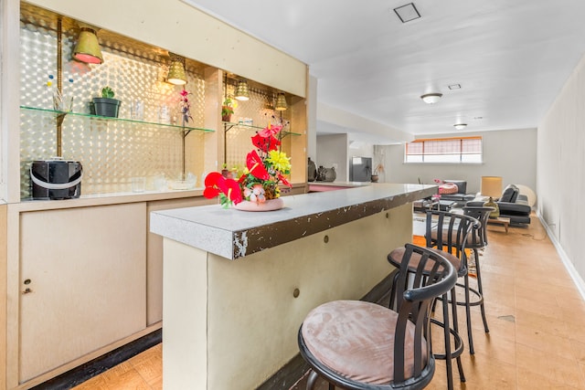 kitchen featuring fridge, a kitchen breakfast bar, baseboards, and open floor plan