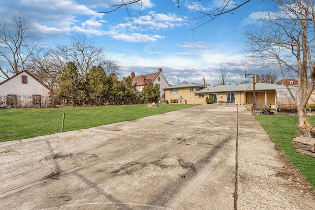 exterior space featuring a front lawn, driveway, and fence