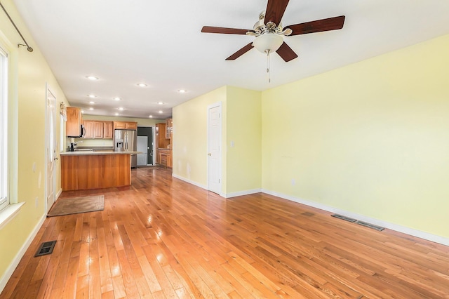 unfurnished living room featuring light wood-style floors, visible vents, and baseboards