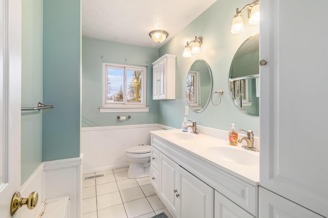 bathroom with tile patterned flooring, double vanity, toilet, and a sink