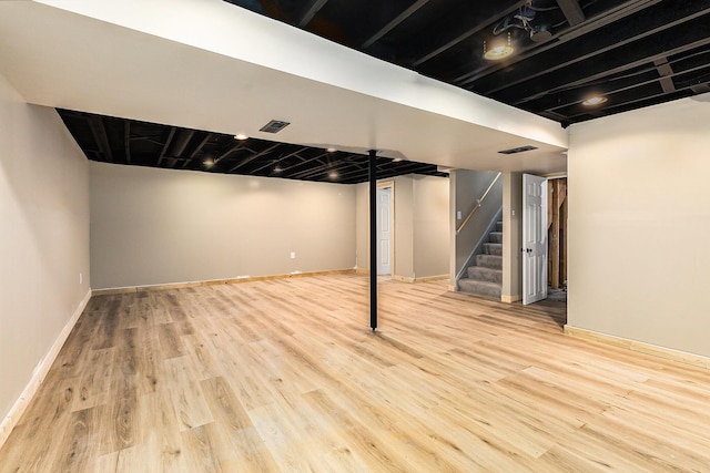 finished basement with stairs, visible vents, wood finished floors, and baseboards