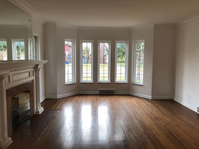 unfurnished living room with a fireplace with flush hearth, wood finished floors, visible vents, and a wealth of natural light