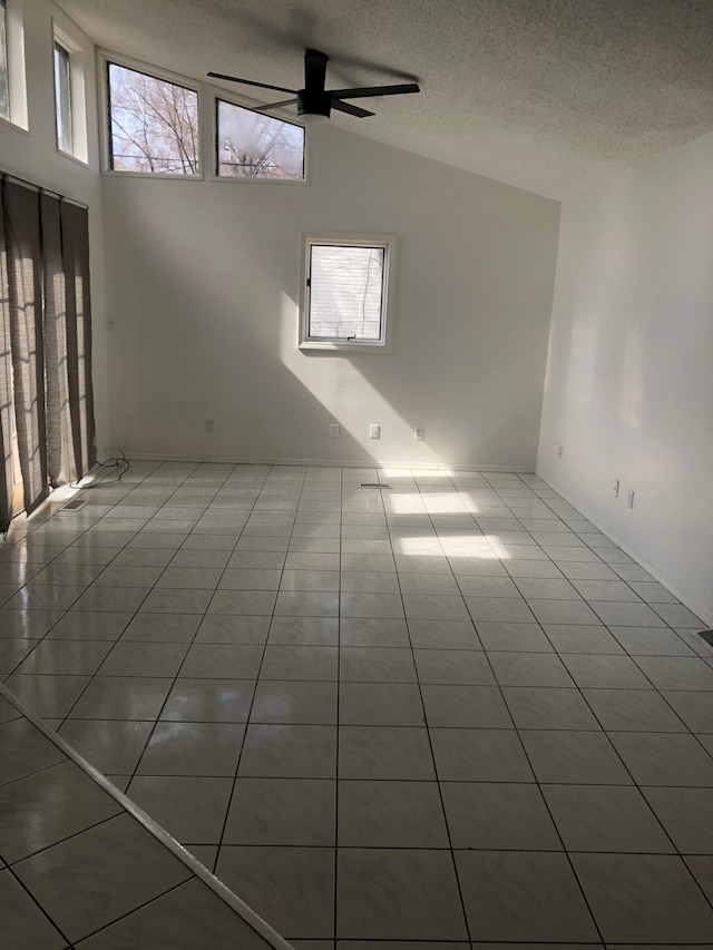 empty room featuring tile patterned floors, a textured ceiling, ceiling fan, and vaulted ceiling