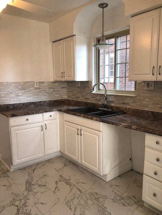 kitchen with backsplash, decorative light fixtures, marble finish floor, white cabinetry, and a sink