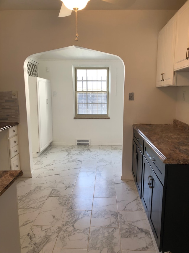 kitchen featuring visible vents, arched walkways, dark countertops, and marble finish floor