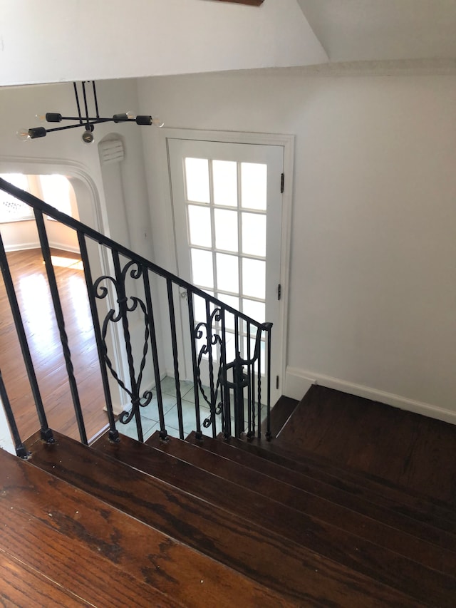 stairway with wood finished floors, baseboards, and a wealth of natural light