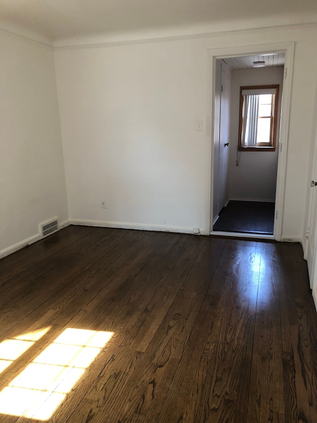 spare room with dark wood finished floors, baseboards, and visible vents