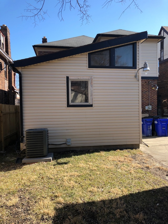 back of property with central air condition unit, a yard, and fence