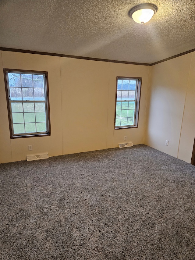 carpeted empty room featuring visible vents, a textured ceiling, and crown molding