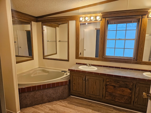 full bath with a garden tub, double vanity, wood finished floors, a textured ceiling, and a sink