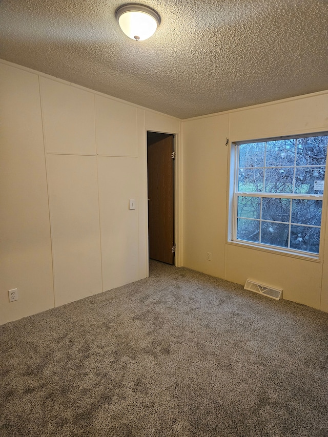 unfurnished bedroom with carpet flooring, visible vents, and a textured ceiling