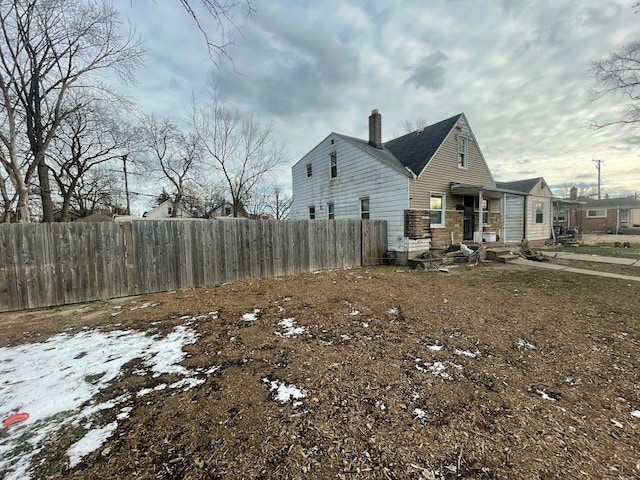 view of property exterior featuring a chimney and fence