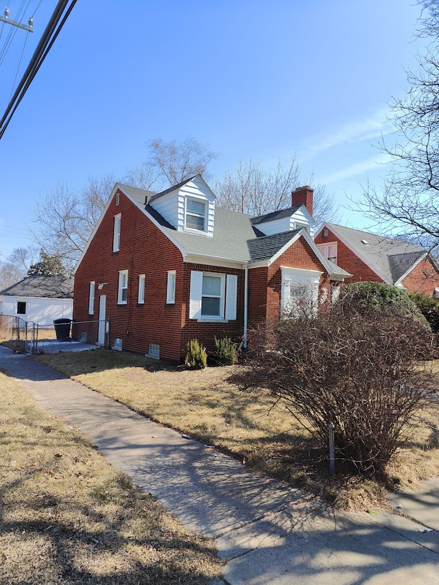 view of front facade featuring brick siding, a chimney, and a front lawn