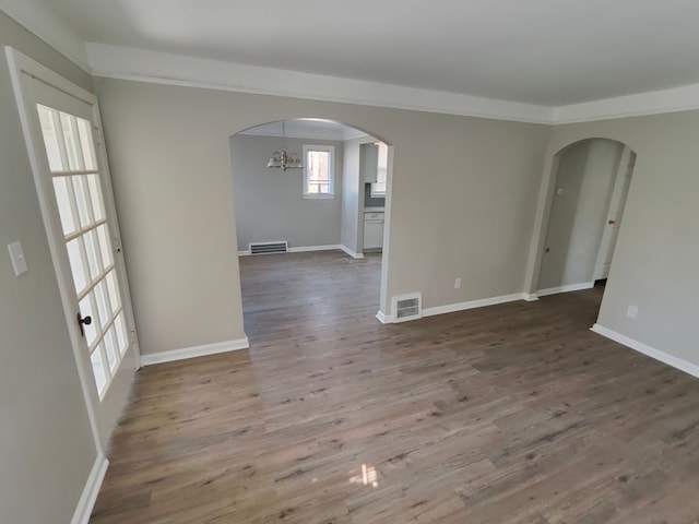 spare room with visible vents, arched walkways, and wood finished floors