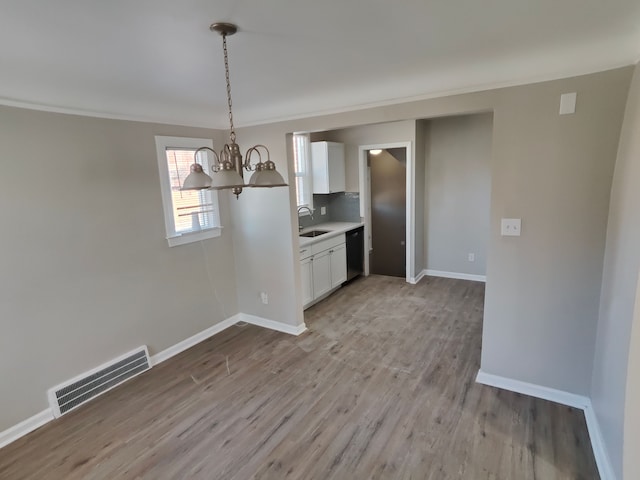 unfurnished dining area featuring a chandelier, visible vents, baseboards, and a sink