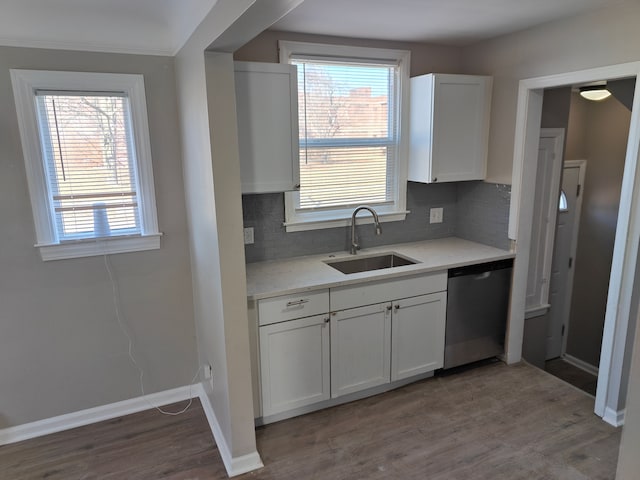 kitchen featuring a sink, tasteful backsplash, wood finished floors, light countertops, and dishwasher