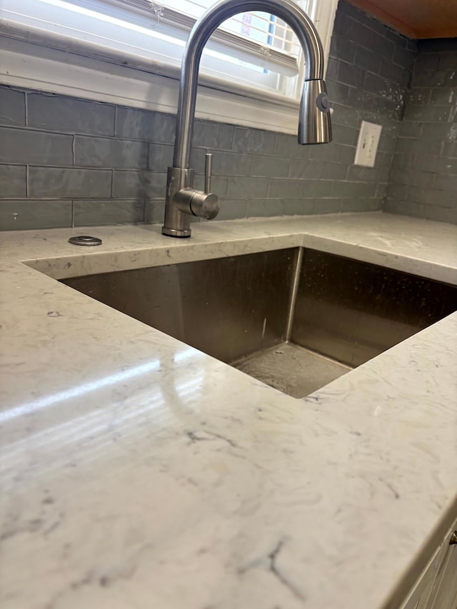 room details with light stone countertops, concrete block wall, and a sink