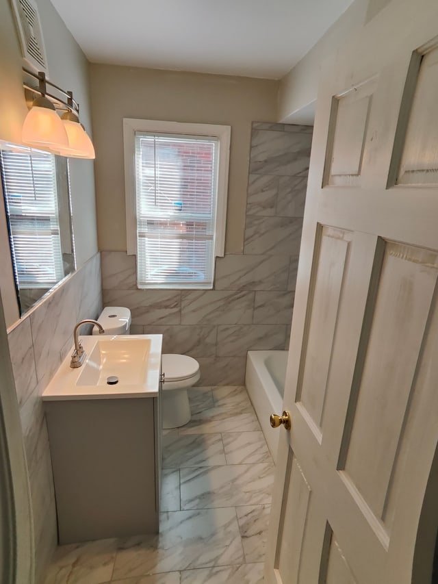 bathroom with a wealth of natural light, marble finish floor, toilet, and vanity