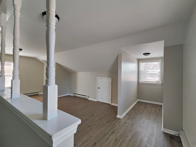 bonus room featuring a baseboard heating unit, lofted ceiling, and wood finished floors