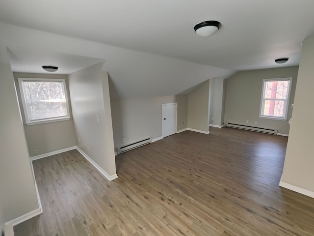 additional living space with vaulted ceiling, wood finished floors, baseboards, and a baseboard radiator