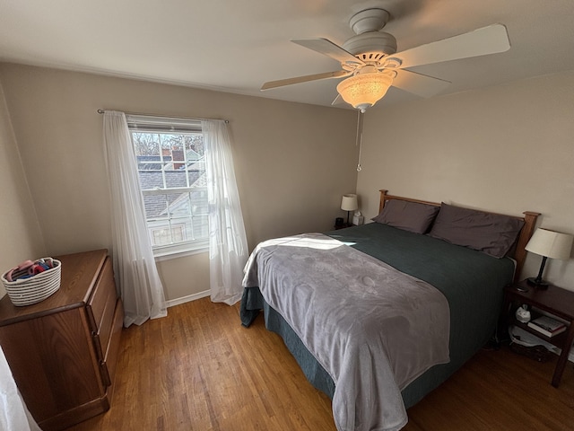 bedroom featuring baseboards, light wood-style floors, and a ceiling fan