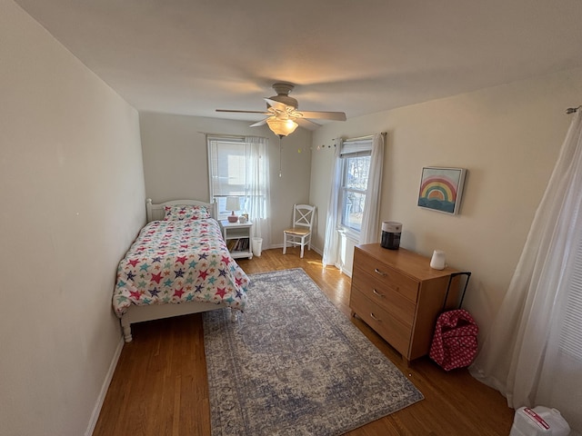 bedroom featuring ceiling fan, baseboards, and wood finished floors