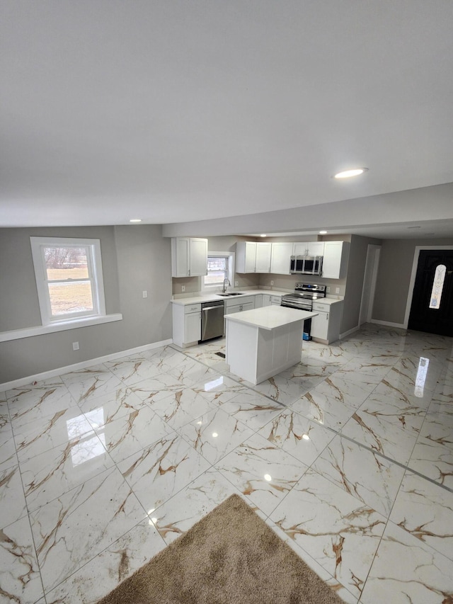 kitchen featuring a center island, marble finish floor, stainless steel appliances, and light countertops