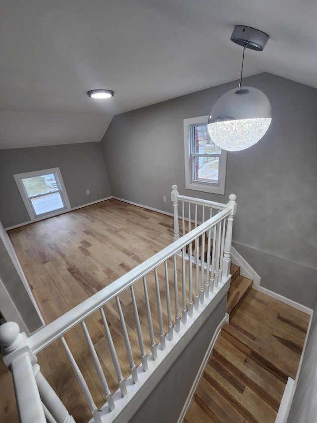 staircase featuring vaulted ceiling, wood finished floors, and baseboards