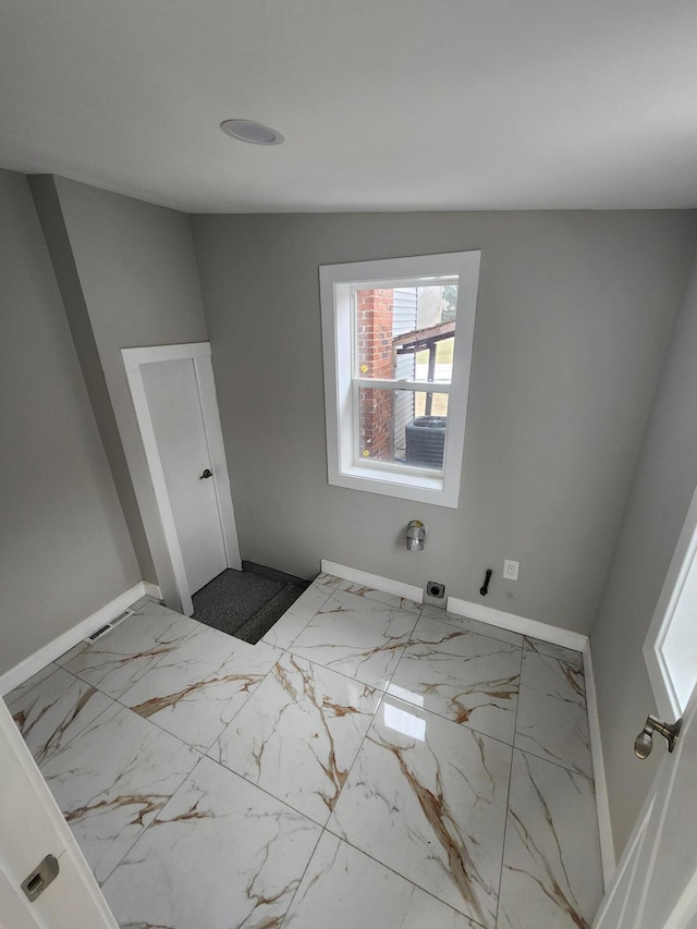 unfurnished room with marble finish floor and baseboards