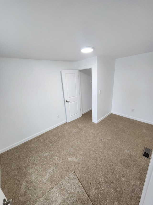 empty room featuring visible vents, carpet floors, and baseboards