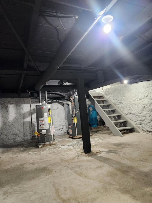 unfinished basement featuring stairs, heating unit, and water heater