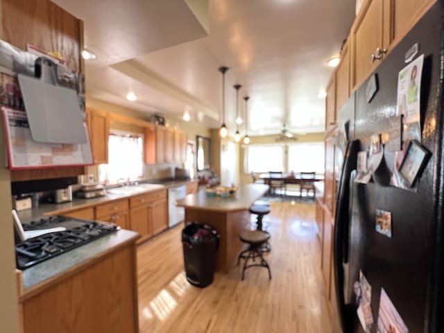 kitchen with light wood-type flooring, a center island, gas stovetop, freestanding refrigerator, and white dishwasher