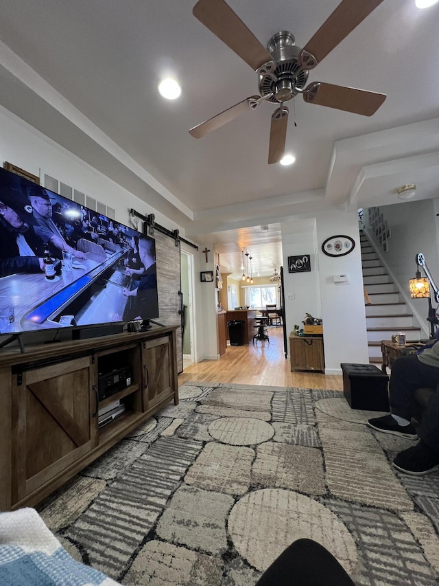 living room featuring wood finished floors, recessed lighting, a barn door, ceiling fan, and stairs