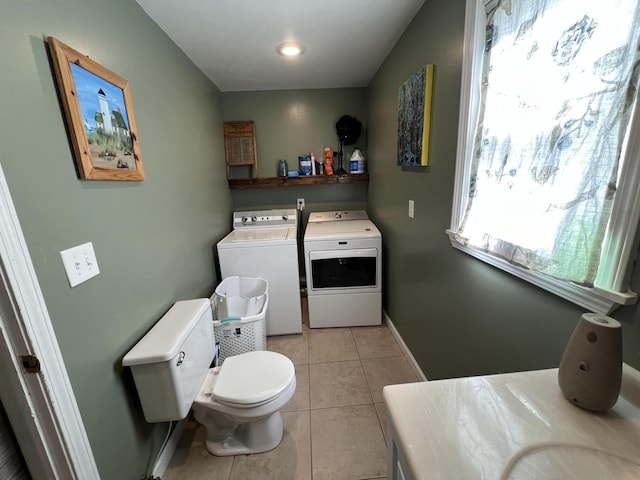 laundry area featuring light tile patterned floors, baseboards, laundry area, and washing machine and clothes dryer