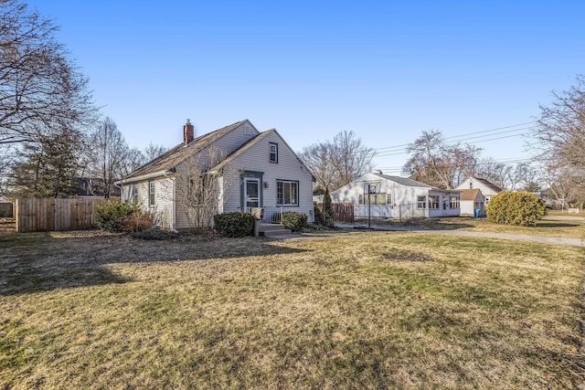 view of front facade featuring a front yard, fence, and a chimney