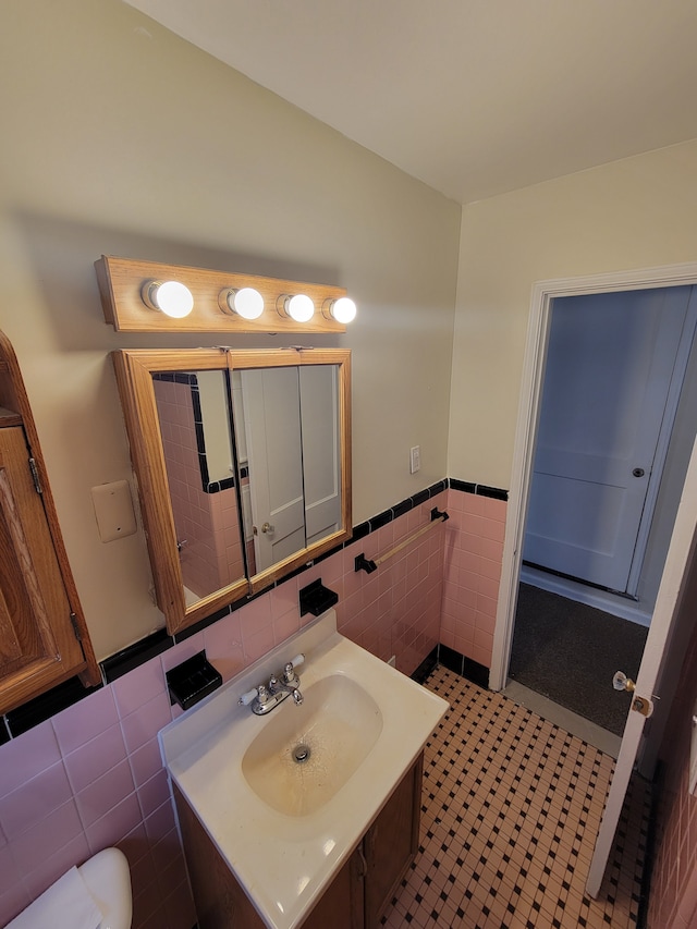 bathroom featuring toilet, tile walls, wainscoting, and vanity