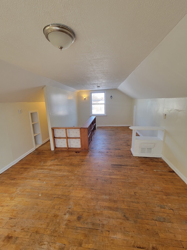 bonus room with baseboards, a textured ceiling, vaulted ceiling, and hardwood / wood-style flooring