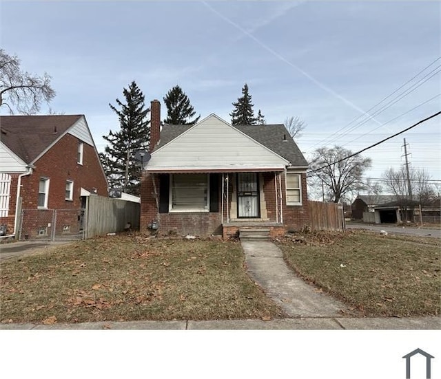 bungalow featuring brick siding, a chimney, and fence