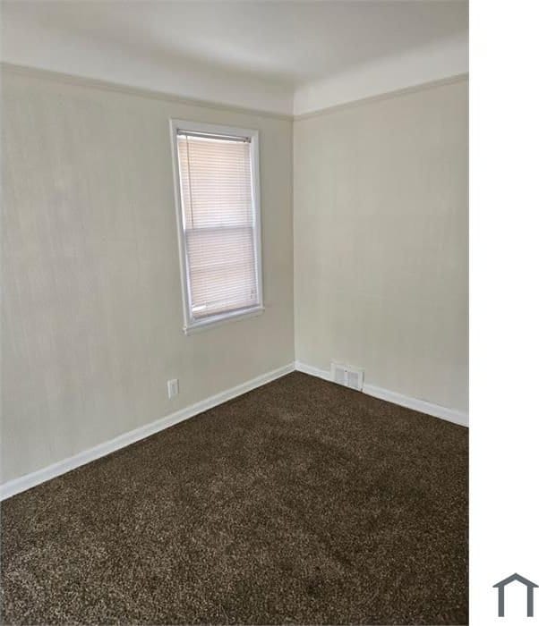 spare room with visible vents, baseboards, and dark colored carpet