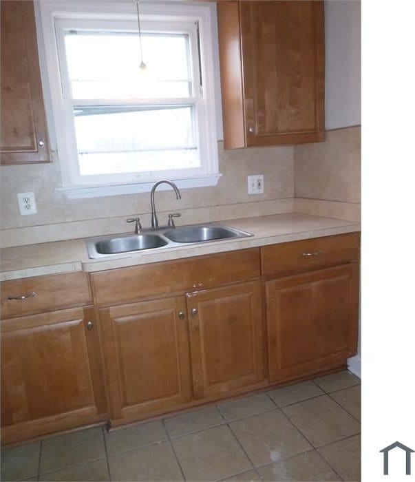 kitchen with light countertops, pendant lighting, brown cabinets, and a sink