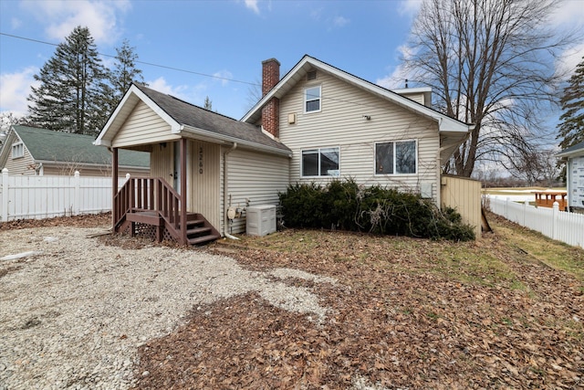 back of property featuring roof with shingles, a chimney, and fence