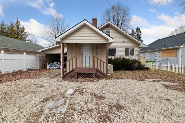 back of house with a carport, a chimney, and fence