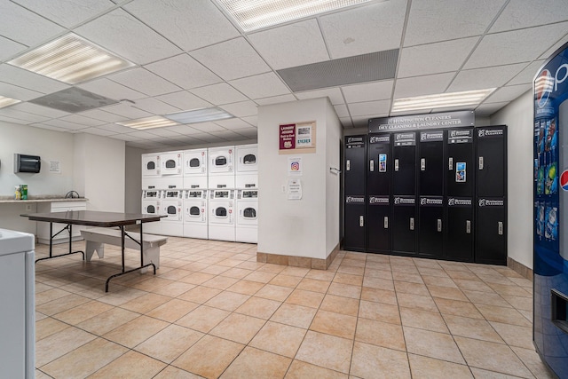 shared laundry area featuring stacked washer / dryer, washer and clothes dryer, baseboards, and light tile patterned floors