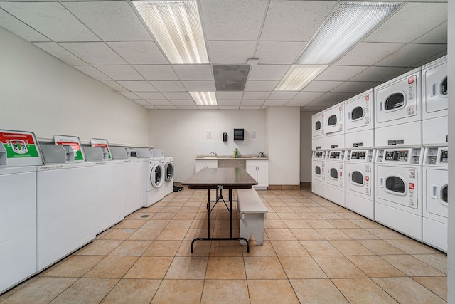 shared laundry area featuring stacked washer and clothes dryer, washer and clothes dryer, light tile patterned floors, and a sink