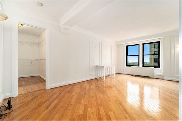 empty room with baseboards, radiator, light wood-style flooring, and crown molding