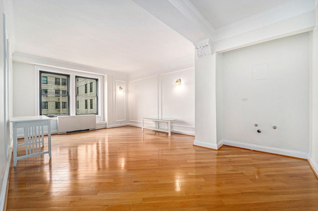 empty room with crown molding, light wood-style floors, baseboards, and radiator heating unit