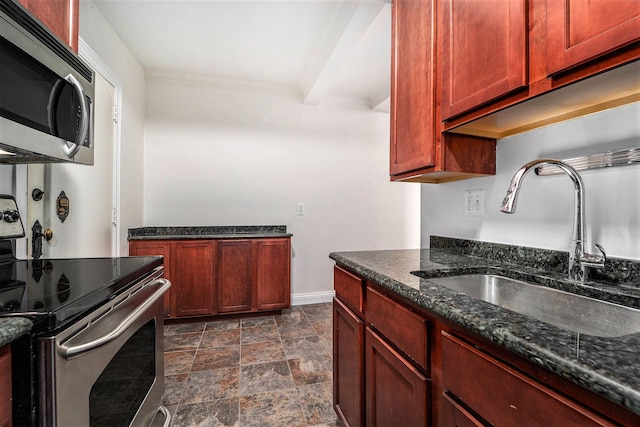 kitchen with a sink, reddish brown cabinets, stone finish floor, and appliances with stainless steel finishes