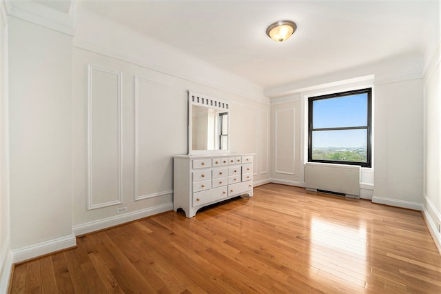unfurnished bedroom featuring light wood finished floors and radiator heating unit