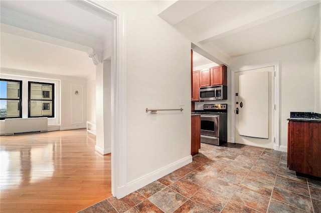 hall featuring baseboards, ornamental molding, and stone finish floor
